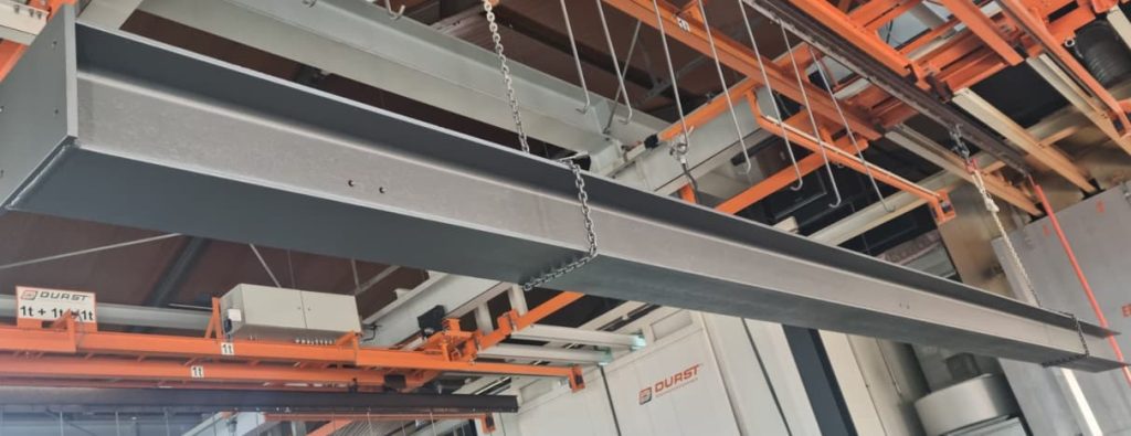 Fertig pulverbeschichteter Stahlträger nach dem Einbrennen – hängt in der Beschichtungsanlage bei K. H. Seger Metallbeschichtung zur Abkühlung.